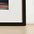Black frame leaning against a white wall with a wooden floor.