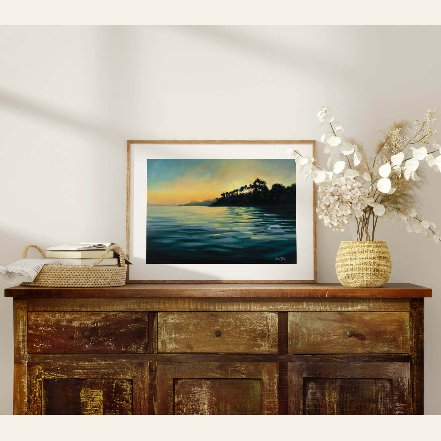 Framed artwork on a wooden console table with decorative items.