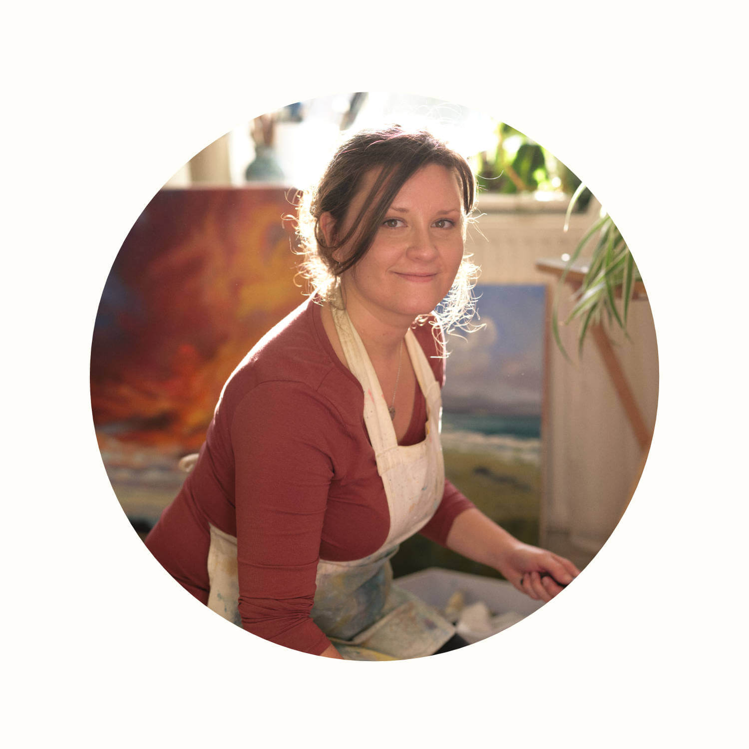 Rachel Painter smiling in her artist studio in Cornwall with paint brush in hand