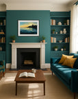 Living room with teal walls, a blue sofa, and a fireplace with a moody artwork of a sunset over water.