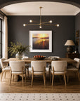 Large contemporary landscape fine art print featuring a dramatic colourful sunset, styled as statement wall art in an elegant dining room interior with deep charcoal walls. By landscape painter, Rachel Painter, the view is inspired by a view looking up the Helford River estuary in Cornwall on a summers evening.