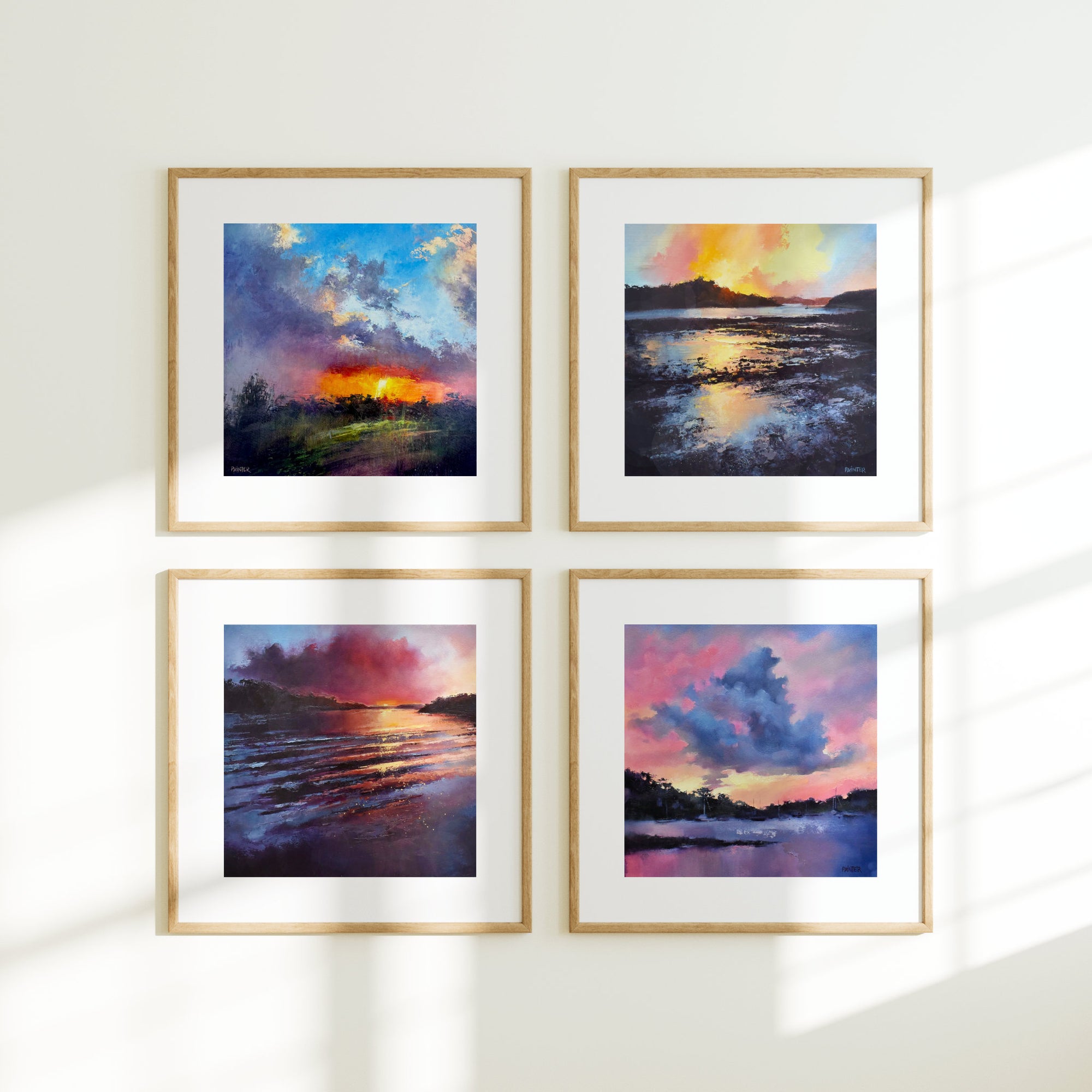 Four framed mini art prints of sunset landscapes with colourful skies on a white wall.