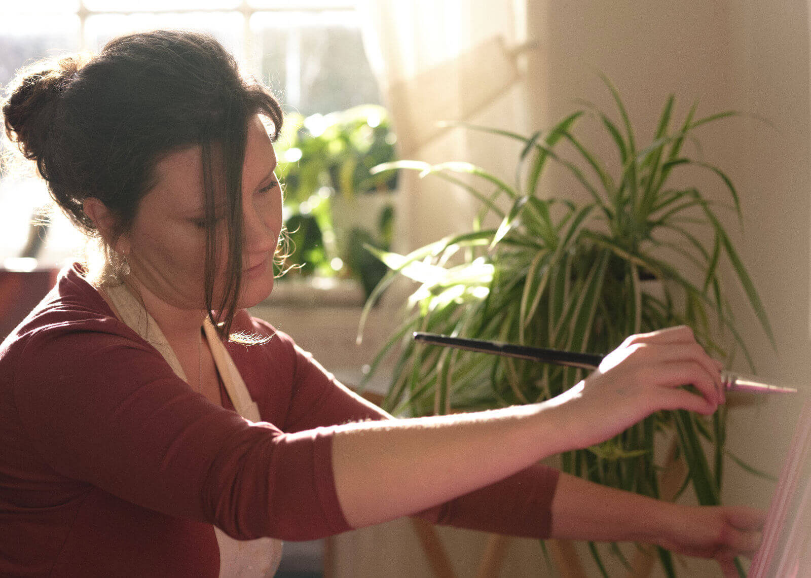 Rachel creating a landscape oil painting in her artist studio in Cornwall with her paint brush