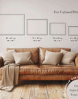 Brown leather sofa with pillows in a room setting, featuring a size chart for unframed prints.