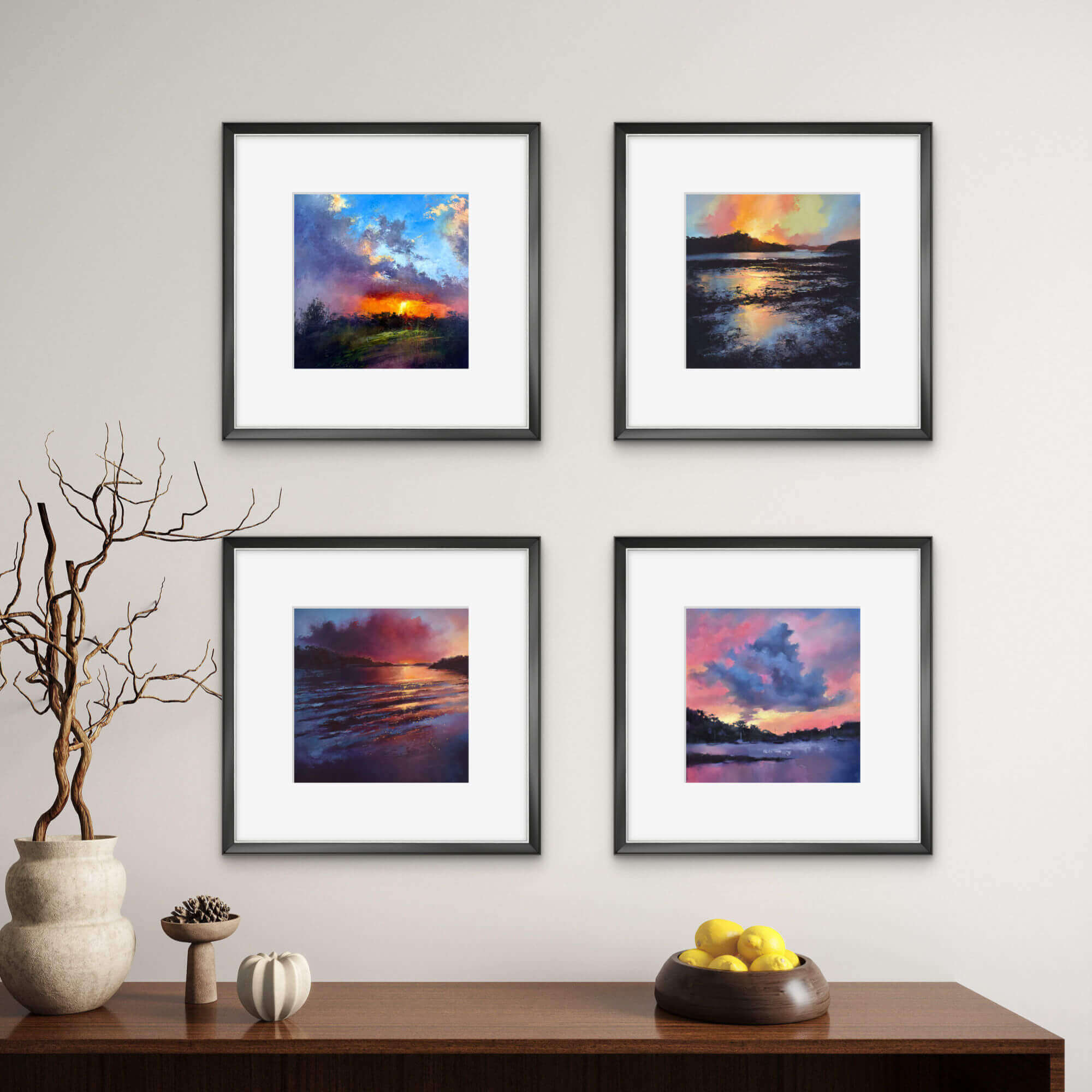 Four framed landscape mini prints of sunsets on a wall above a wooden console table.