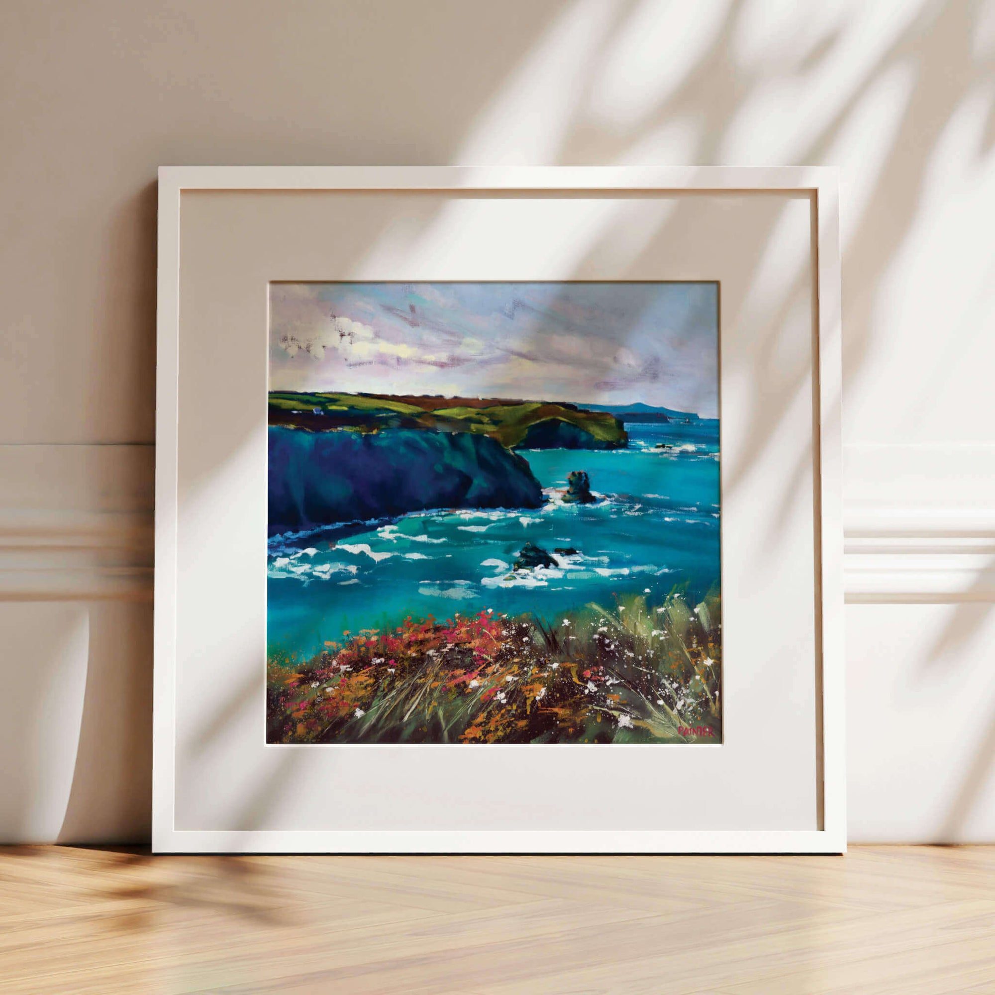 Upon A Pavement Of Sapphire, white framed coastal art prints of cliffs over turquoise sea near Portreath with pink sea flowers by Cornwall artist Rachel Painter