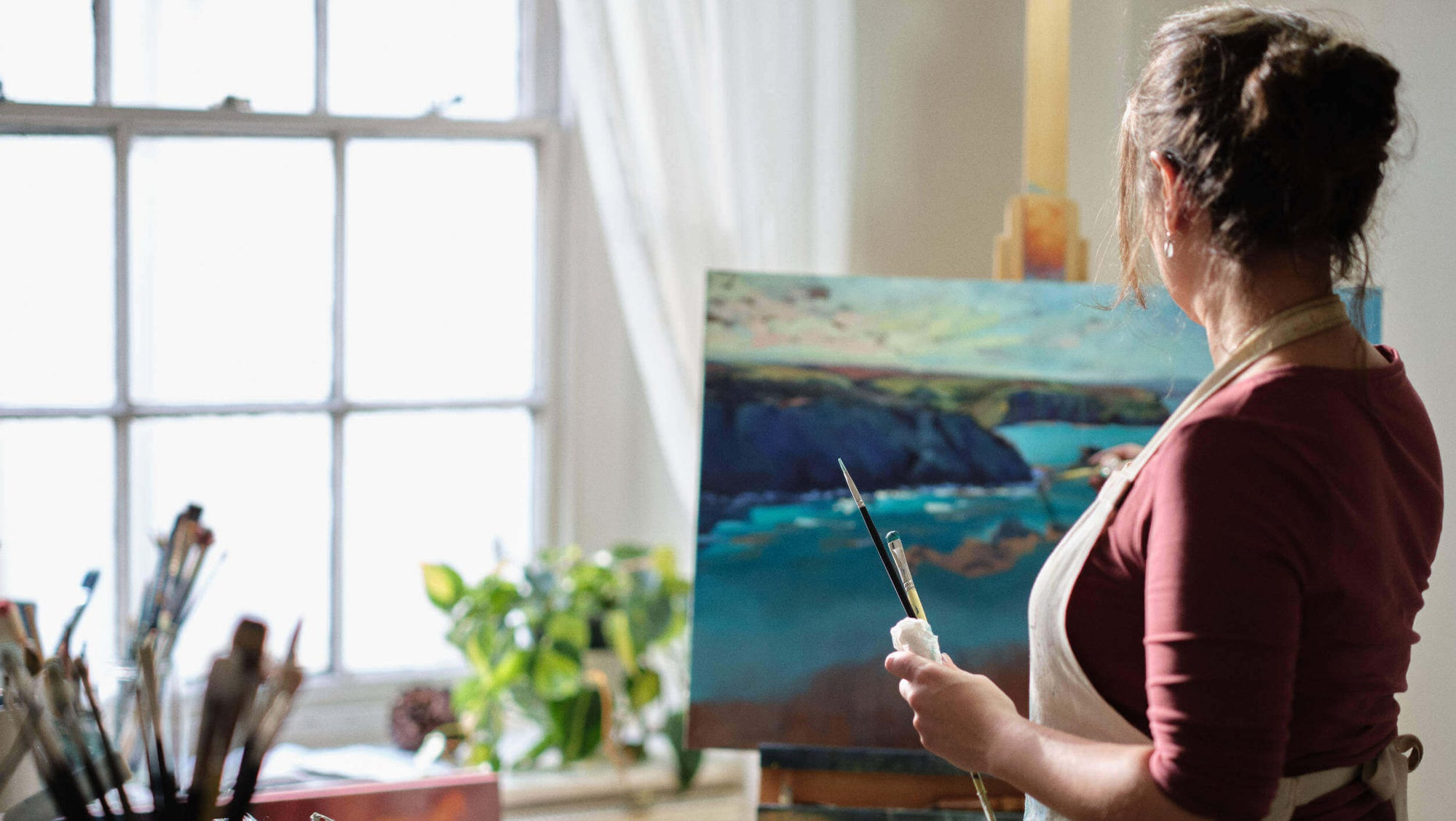 Rachel Painter painting a landscape art commission at her easel in her studio