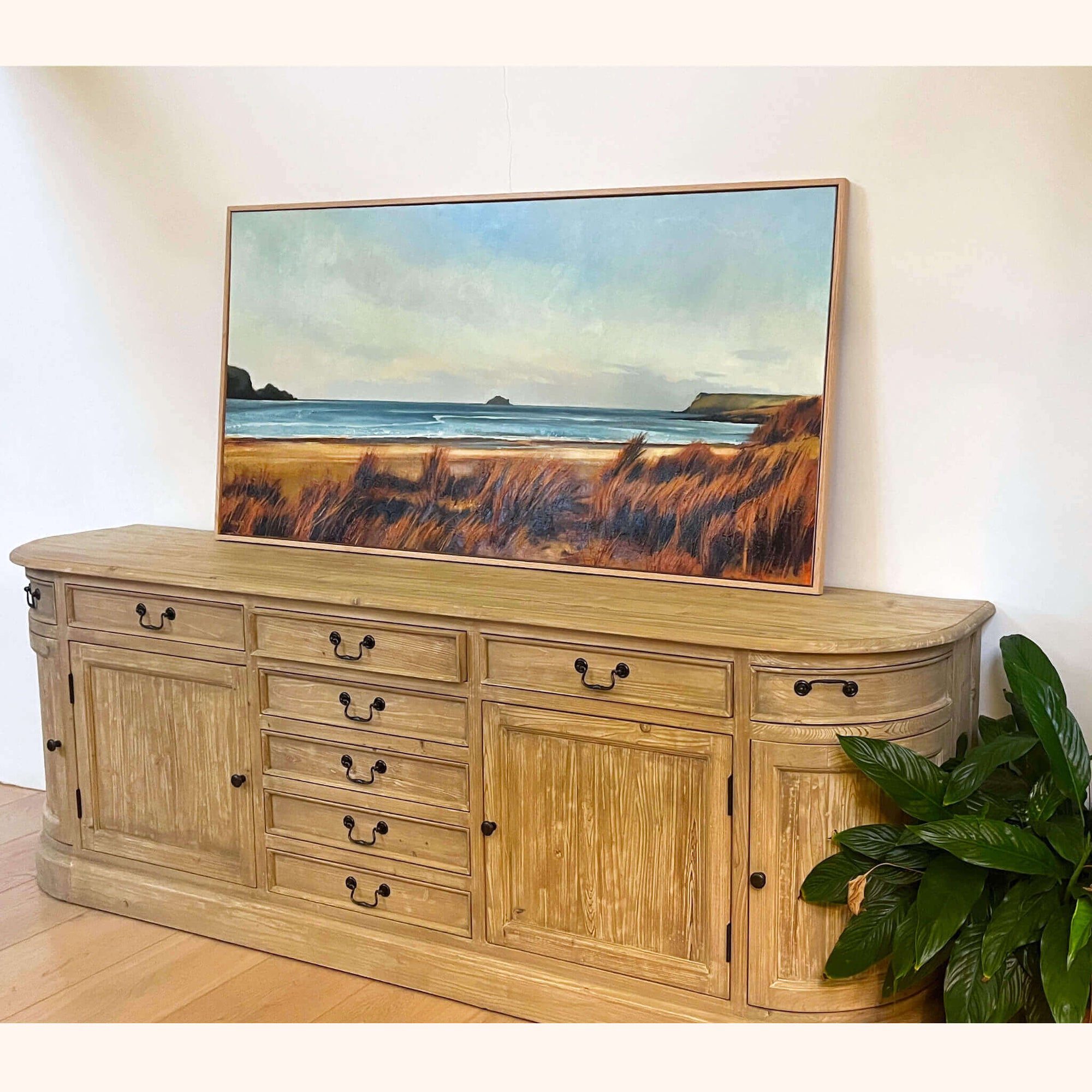 Wooden sideboard with a large commissioned landscape painting of a Polzeath beach scene in Cornwall by Rachel Painter.