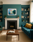 Living room with teal walls, a blue sofa, and a fireplace with a landscape artwork of a sunset over water
