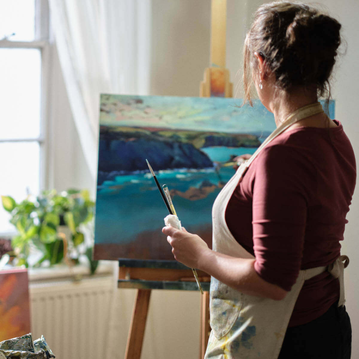Rachel Painter painting an art commission at her easel in her studio