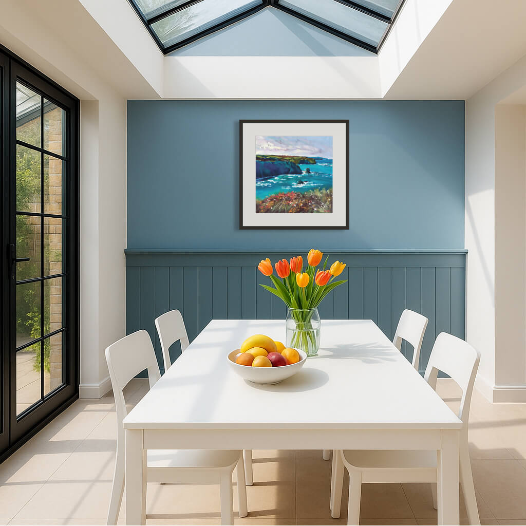 Framed coastal artwork in dining room with a white table, chairs, and a vase of flowers against a blue wall - by Rachel Painter, contemporary seascape artist