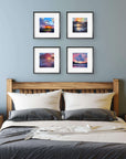Bedroom with wooden headboard and four framed sunset landscape pictures on the wall.