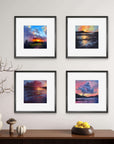 Four framed landscape mini prints of sunsets on a wall above a wooden console table.