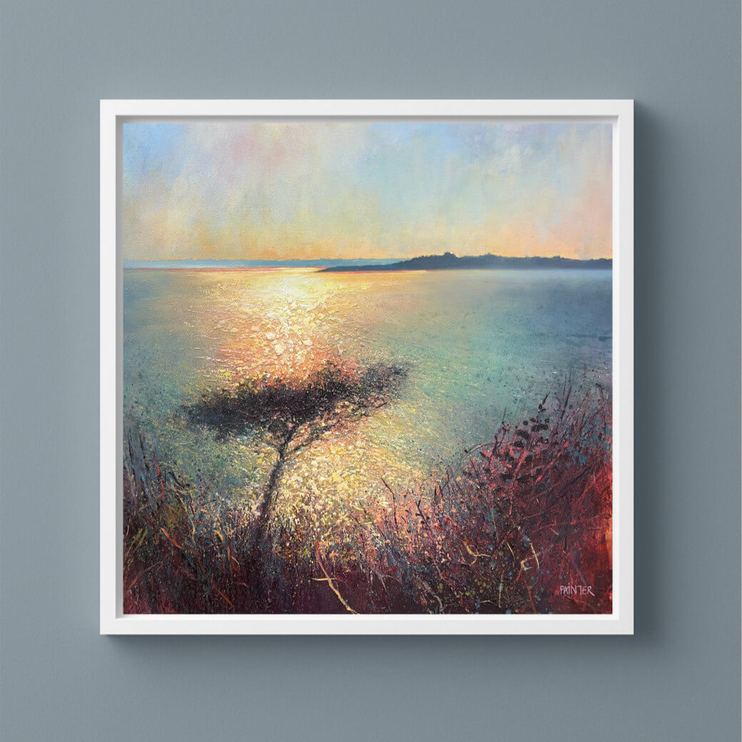 Framed warm painting of a sunset over water with a tree on a cool blue neutral wall